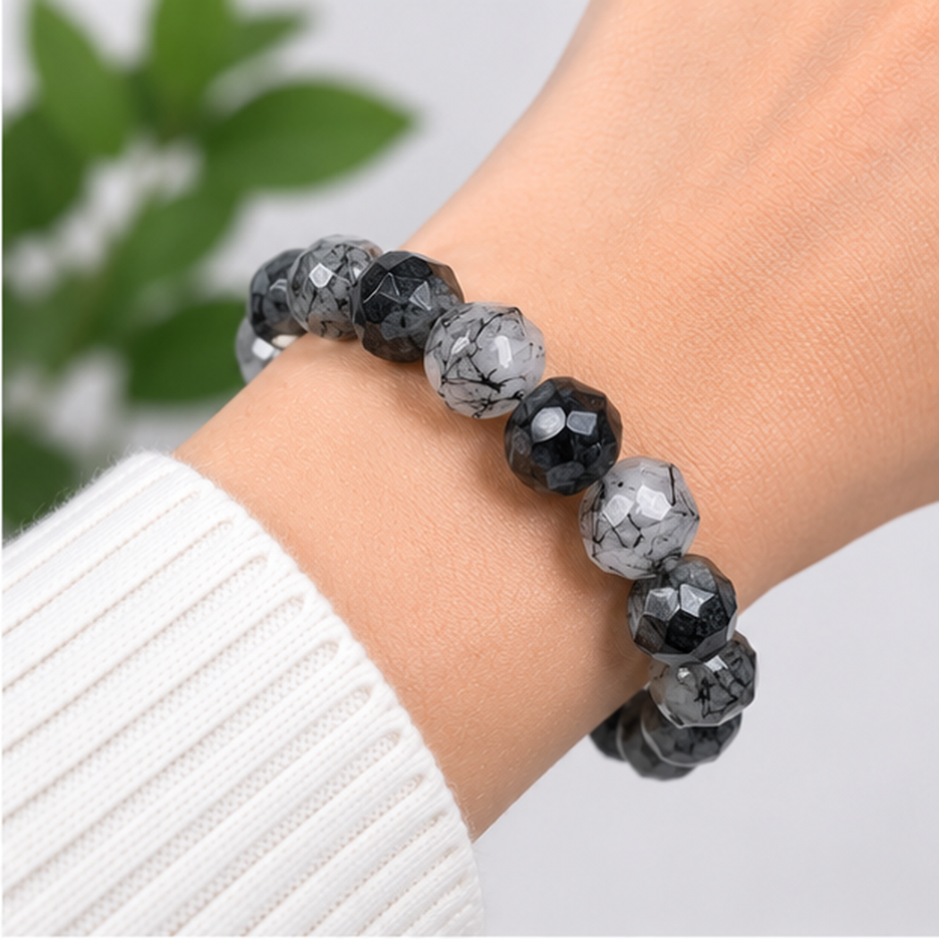 Bracelet en cristal noir naturel 8mm porté au poignet avec perles facettées et inclusions de tourmaline noire