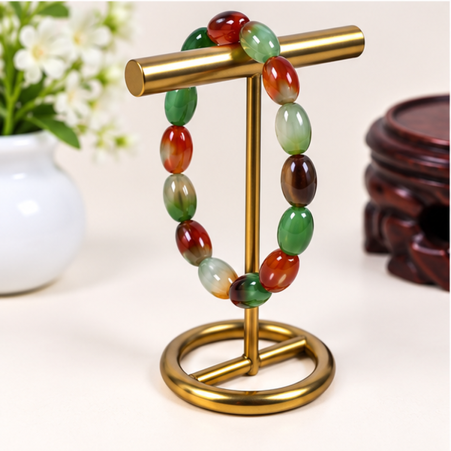 Bracelet en agate paon naturelle aux nuances vert, brun et rouge présenté sur un support
